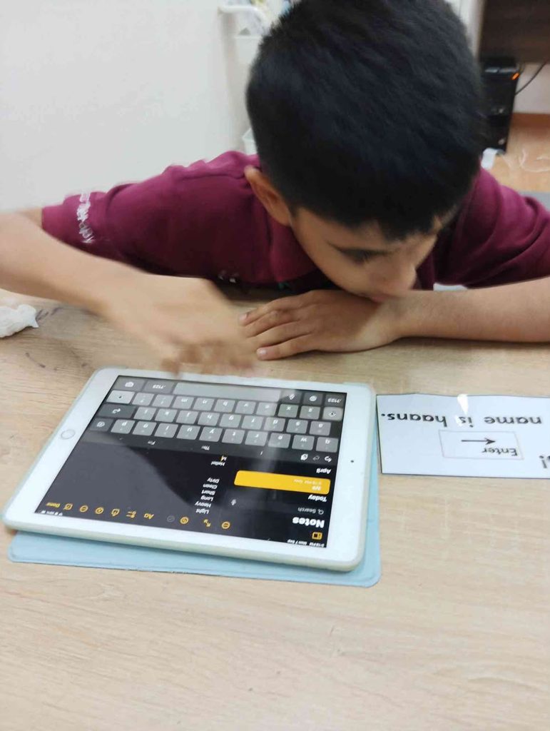 Boy using an ipad which is an AAC devices to learning spelling