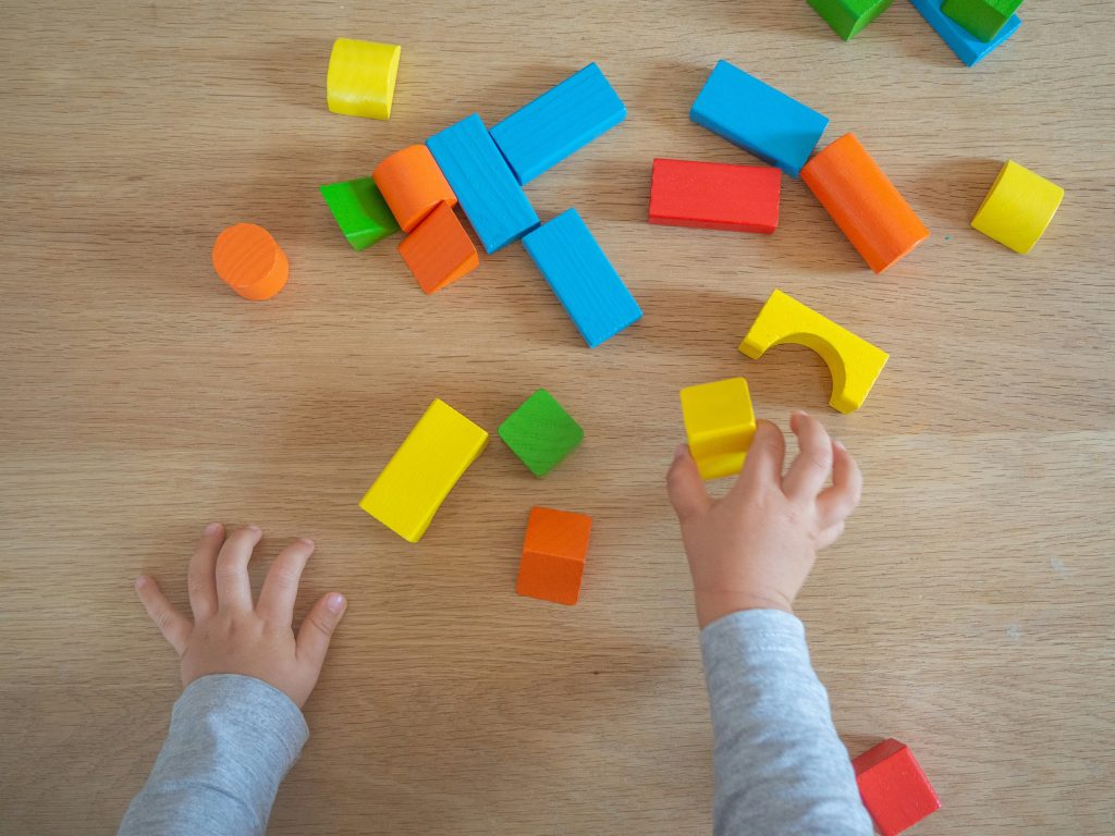 Hands of a child with building blocks scattered